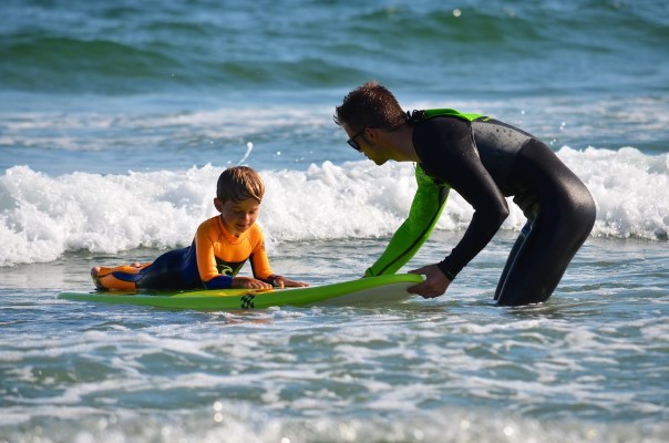 surfing instructor helping young child