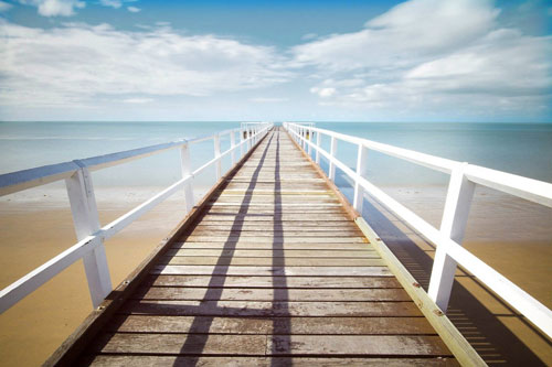 narrow pier stretching out to sea taken with a wide-angle lens