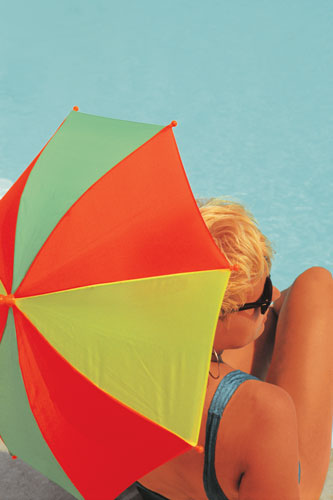 woman holding umbrella facing very blue pool