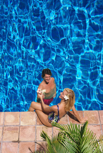 a couple near the edge of a pool with very deep blue water