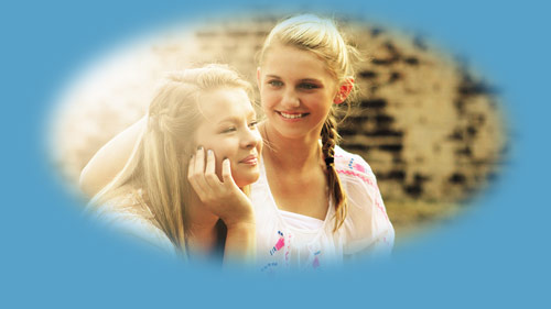 two women conversing, smiling with sun shining in from left side